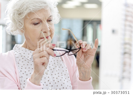 Interested old woman choosing eyewear Interested old woman choosing eyewear 30373051