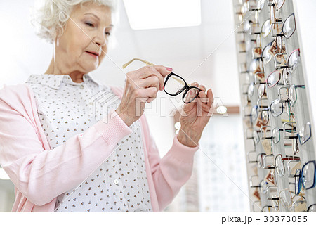 Concentrated mature woman keeping eyewear 30373055