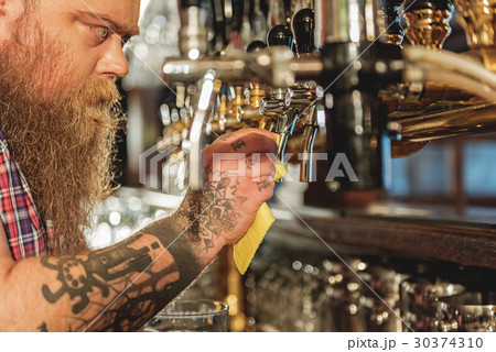 Calm bearded male washing beer tap Calm bearded male washing beer tap 30374310