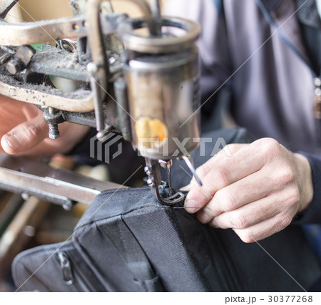 Tailor man sews up a bag in a workshop 30377268