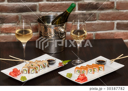 Two sets of sushi rolls with chopsticks and wine Two sets of sushi rolls with chopsticks and wine 30387782