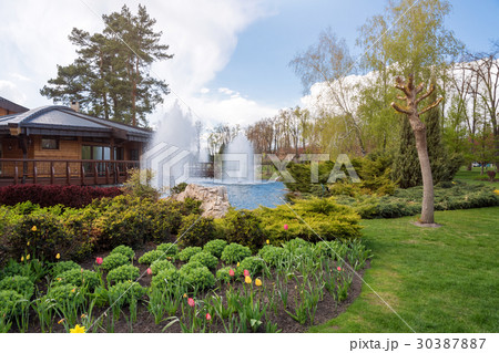 Ornamental gardens with lake, blooming bushes and 30387887