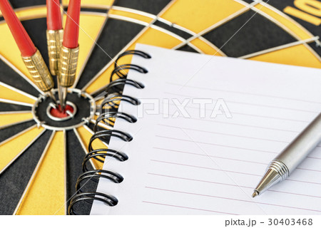 pen on notebook with darts on bullseye background pen on notebook with darts on bullseye background 30403468
