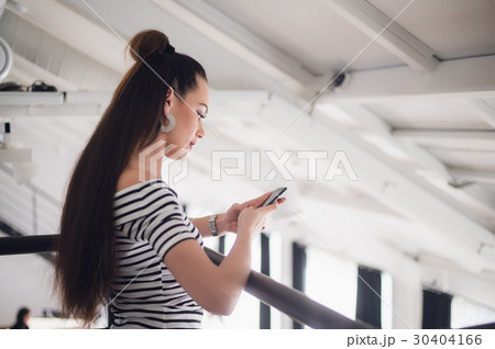 Texting woman sitting at the table and holding the 30404166
