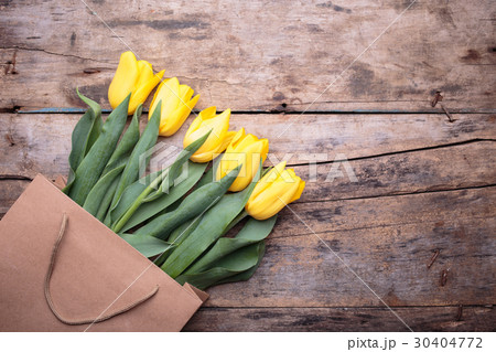 Bunch of yellow tulips in paper bag on wood 30404772
