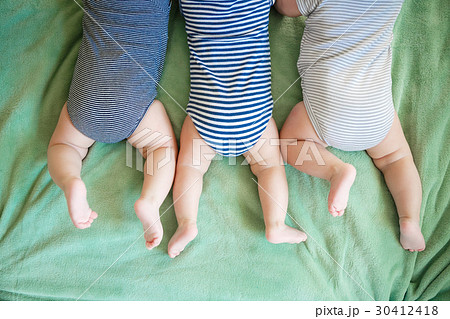 Newborn triplets lie on a stomach on a blanket 30412418