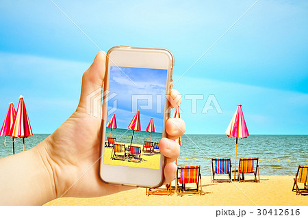 Hand holding smart phone with Chairs and umbellar Hand holding smart phone with Chairs and umbellar 30412616