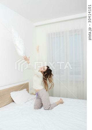 Woman in pajama smiling and throwing a pillow 30414101