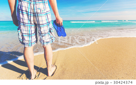 Man holding his sandals at the shore 30424374