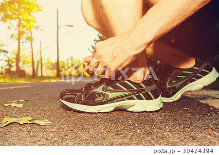 Male jogger tying his running shoes Male jogger tying his running shoes 30424394