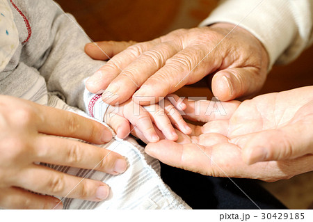赤ちゃんの手とおじいちゃんの手とお母さんの手の写真素材