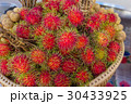 Red rambutan on brown wicker basket. 30433925