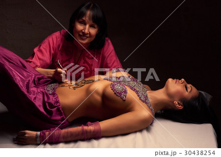 Mehendi artist paints an ornament of henna  30438254