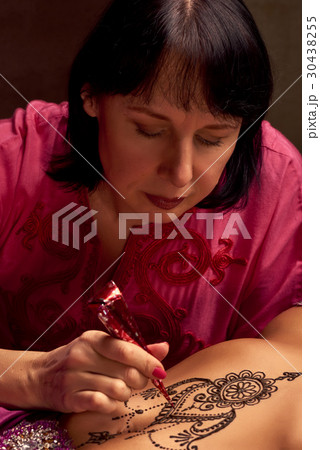 Mehendi artist paints an ornament of henna  30438255