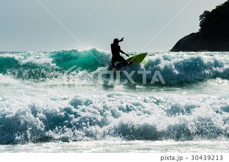 A surfer silhouette man having fun surfing wave 30439213