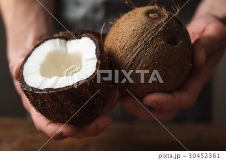 Fresh coconut and half in hands close up view 30452361