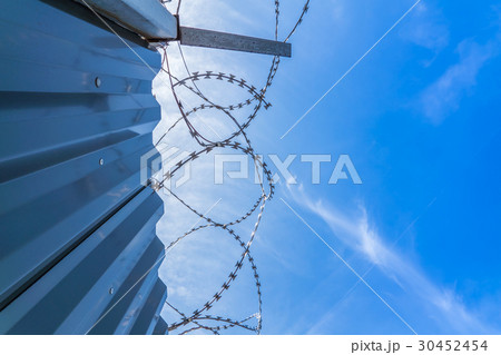 Fence with barb wire and blue sky 30452454
