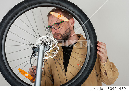 Bearded man checks the fastening of front wheel. 30454489