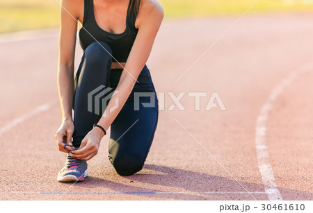 Female runner tying lace on stadium. 30461610