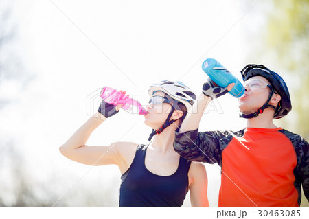 Bicyclists drink water from bottle 30463085
