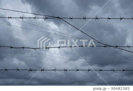 Silhouette of barbed wire over dark storm clouds 30482385
