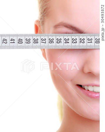Fitness girl fit woman covering her eyes with measuring tape 30493872