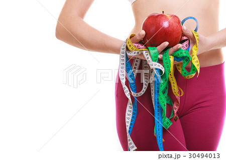 Closeup of woman holding apple and tape measures. 30494013