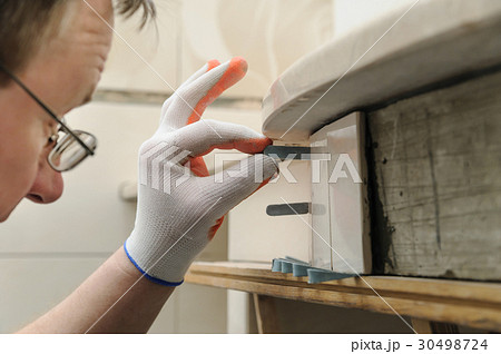 Worker is propping tile. 30498724