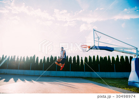 Young man jumping and making a fantastic slam dunk 30498974