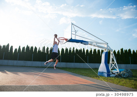 Young man jumping and making a fantastic slam dunk 30498975