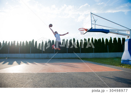 Young man jumping and making a fantastic slam dunk Young man jumping and making a fantastic slam dunk 30498977