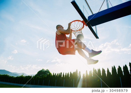 Young man jumping and making a fantastic slam dunk Young man jumping and making a fantastic slam dunk 30498979