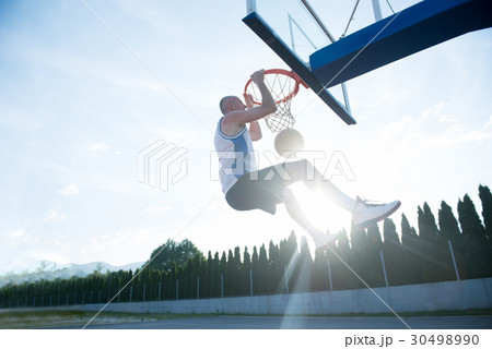 Young man jumping and making a fantastic slam dunk 30498990