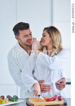 Happy couple cooking breakfast together in the Happy couple cooking breakfast together in the 30499553