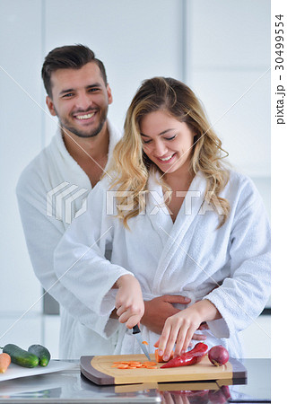 Happy couple cooking breakfast together in the Happy couple cooking breakfast together in the 30499554