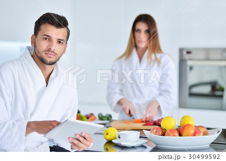 Happy couple cooking breakfast together in the Happy couple cooking breakfast together in the 30499592
