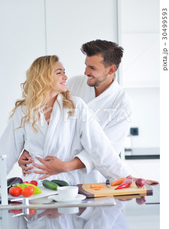 Happy couple cooking breakfast together in the Happy couple cooking breakfast together in the 30499593
