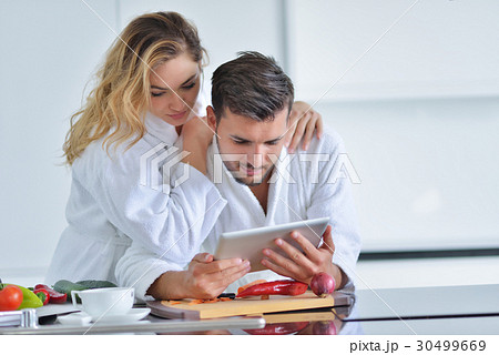 Happy couple cooking breakfast together in the Happy couple cooking breakfast together in the 30499669