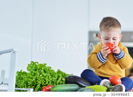 kid girl eating healthy vegetables at kitchen 30499685