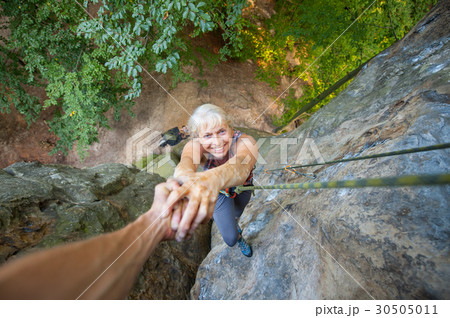 Woman rockclimber is reaching top of the rock Woman rockclimber is reaching top of the rock 30505011