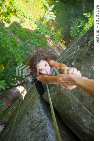 Girl climbing on big rock and hanging on the hand 30505196