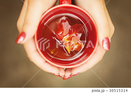 Autumn Leaves and Hot Steaming Cup in Female Hands Autumn Leaves and Hot Steaming Cup in Female Hands 30515314