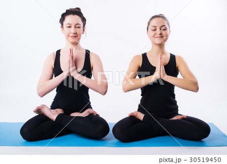 Two women doing yoga and meditating in lotus 30519450