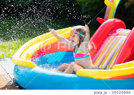 Child in garden swimming pool with slide 30520990