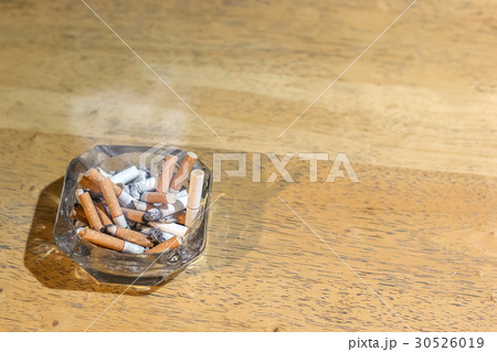 Cigarette butts in the ashtray on wooden table 30526019
