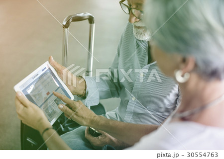 Senior adult couple checking boarding pass on digital tablet Senior adult couple checking boarding pass on digital tablet 30554763