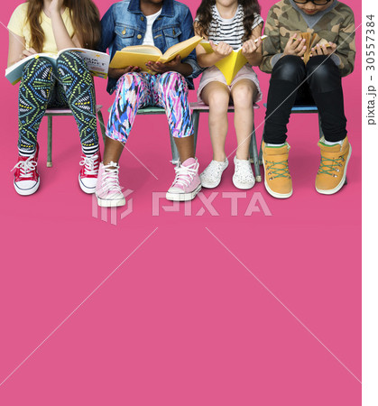 Diverse group of kids sitting in a row reading books Diverse group of kids sitting in a row reading books 30557384