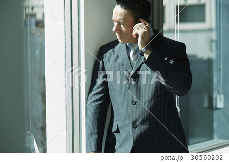 the businessman is looking outside and having a phone call. the businessman is looking outside and having a phone call. 30560202