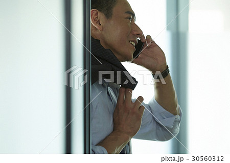 the businessman is happily talking on phone. 30560312