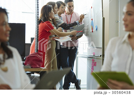 Four of six people discussing a chart on a board Four of six people discussing a chart on a board 30560438